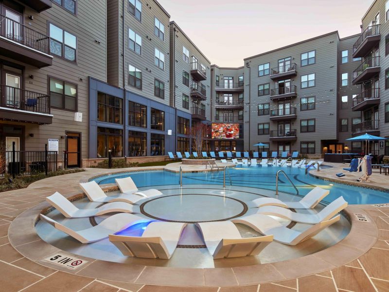 114 Earle Student Living Apartments Outdoor swimming pool surrounded by apartment buildings with lounge chairs in the water.